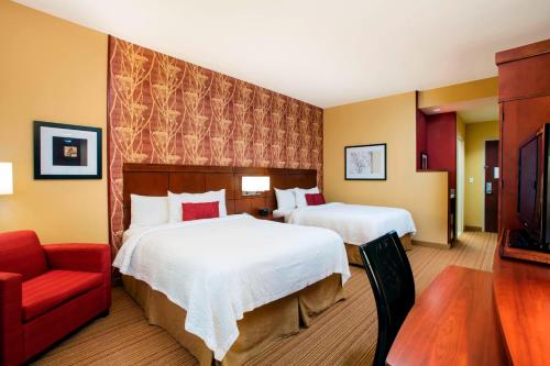 Cette chambre d'hôtel comprend deux lits et un fauteuil rouge. dans l'établissement Courtyard by Marriott Miami Homestead, à Homestead