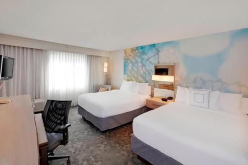 a hotel room with two beds and a desk at Courtyard by Marriott San Antonio Airport/North Star Mall in San Antonio