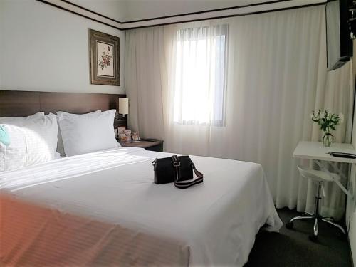 a hotel room with a white bed with a purse on it at Bristol The Time Berrini in Sao Paulo