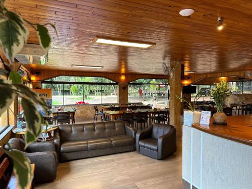 um restaurante com sofás de couro e uma mesa e cadeiras em PARQUE MANANTIAL em Hohenau