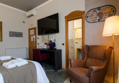 a hotel room with a bed and a chair and a desk at Hotel Maria in Pisa