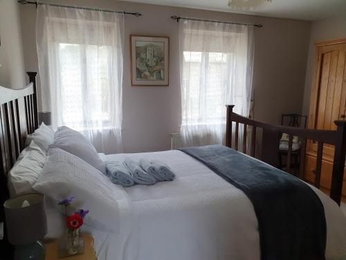 a bedroom with a white bed with towels on it at Mimi's Cottage in Liskeard