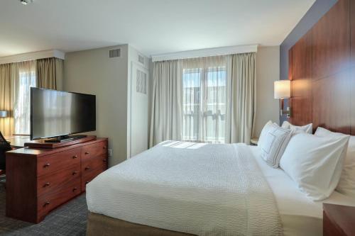 Residence Inn by Marriott Woodbridge Edison/Raritan Center في وودبريدج: غرفة فندقية بسرير وتلفزيون بشاشة مسطحة