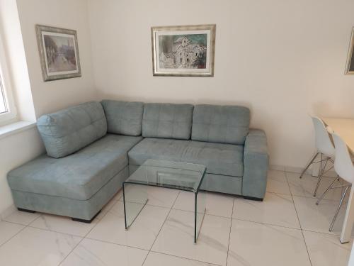 a living room with a blue couch and a glass table at Apartman Daria in Split