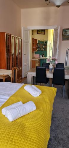 a bedroom with a yellow bed with two towels on it at Oroszlán Apartman in Szeged