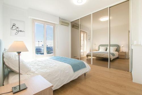 a white bedroom with a bed and a window at Spacieux 3 Pièces de standing au centre de Monaco in Monte Carlo