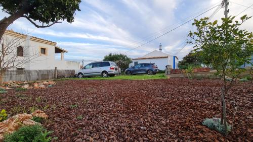 two cars parked in a yard with a church at Monte da ti Luzia in Faro