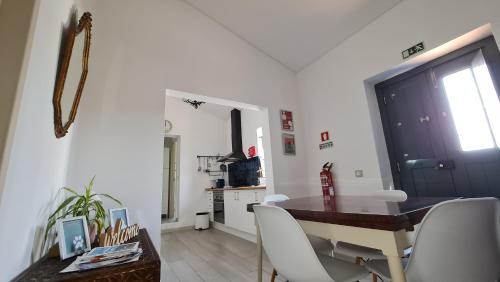a dining room with a table and white chairs at Monte da ti Luzia in Faro