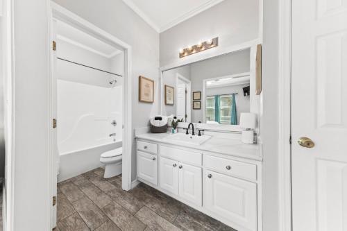 a white bathroom with a sink and a toilet at GulfShores BeachCondo - Pool - FreeParking - SummerTime! - Little Lagoon in Gulf Shores