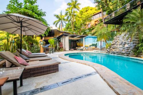a swimming pool with a patio furniture and an umbrella at Boutique Hotel Las Cascadas in Manuel Antonio