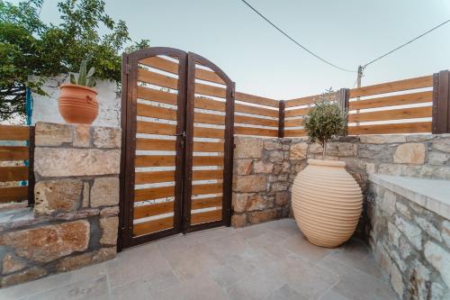 a wooden gate with a vase next to a stone wall at Kythera secrets suites in Viarádhika