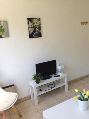 un salon avec une télévision sur une table blanche dans l'établissement Studio à 5 minutes à pied des plages et de la croisette, à Cannes