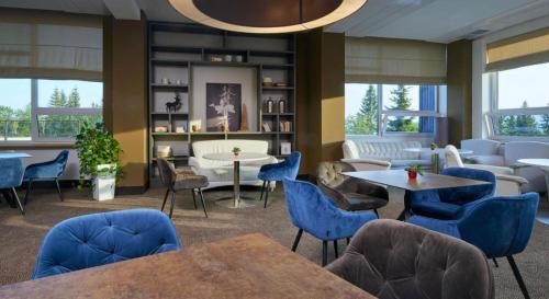 uma sala de espera com cadeiras e mesas azuis em OREA Resort Horizont Šumava em Železná Ruda