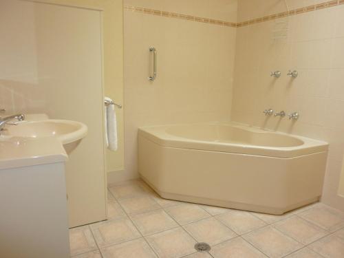 a white bathroom with a tub and a sink at Bayview Apartments in Merimbula