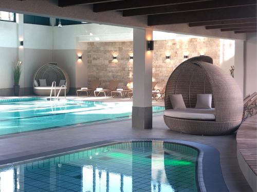 a swimming pool with a wicker chair next to a building at Aquamaris Strandresidenz Rügen in Juliusruh