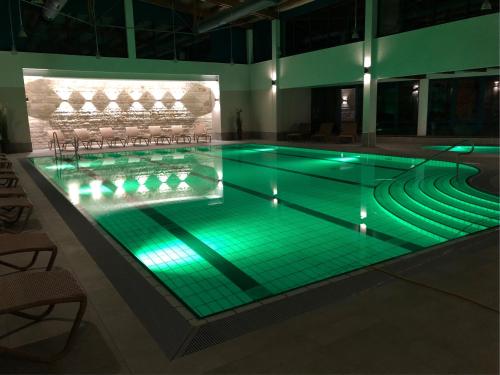a swimming pool with green lights in a building at Aquamaris Strandresidenz Rügen in Juliusruh