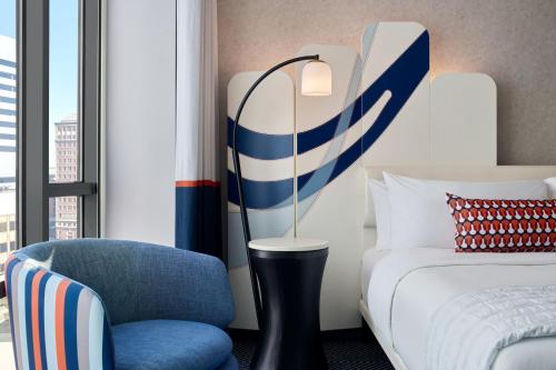 a hotel room with a bed and a blue chair at Le Méridien St. Louis Clayton in Clayton