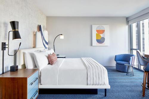 a bedroom with a white bed and a blue chair at Le Méridien St. Louis Clayton in Clayton