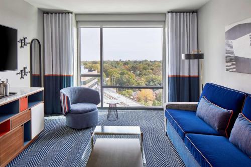 a living room with a blue couch and a large window at Le Méridien St. Louis Clayton in Clayton