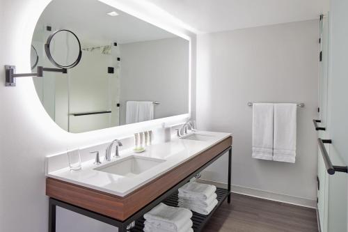 a bathroom with a sink and a large mirror at Le Méridien St. Louis Clayton in Clayton