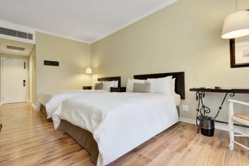 a bedroom with a large white bed and wooden floors at Protea Hotel by Marriott Mahikeng in Mahikeng