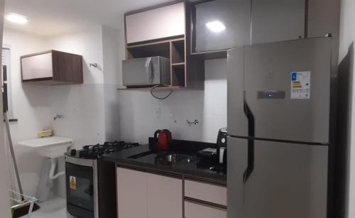uma cozinha com um frigorífico, um fogão e um lavatório em Apartamento barra prime em Barra dos Coqueiros