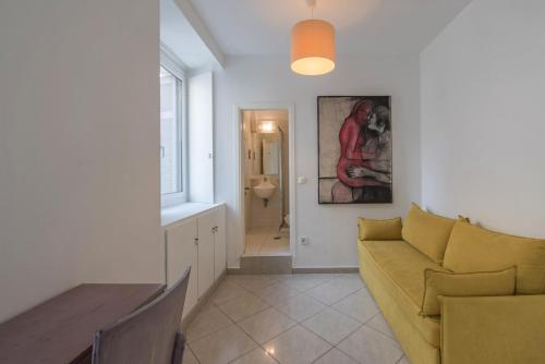 a living room with a yellow couch and a table at Kimon Hotel Athens in Athens