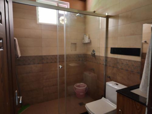 een badkamer met een glazen douche en een toilet bij VanaJyotsna Forest Home in Maraiyūr