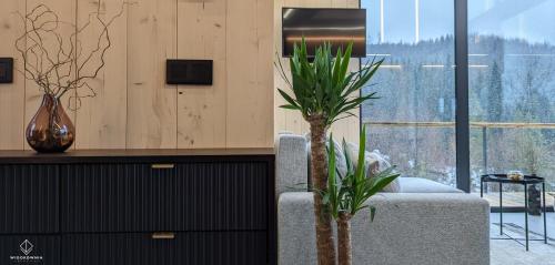 a living room with a couch and two potted plants at Widokownia Brenna in Brenna