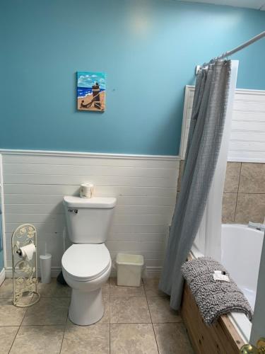 La salle de bains est pourvue de toilettes et d'un mur bleu. dans l'établissement Whispering Waves Cottages, à Shelburne