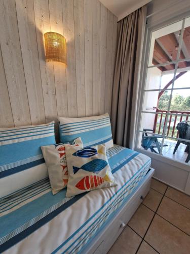 1 dormitorio con cama con almohadas y ventana en Appartements au coeur du golf, proche du lac et vélodyssée, en Biscarrosse