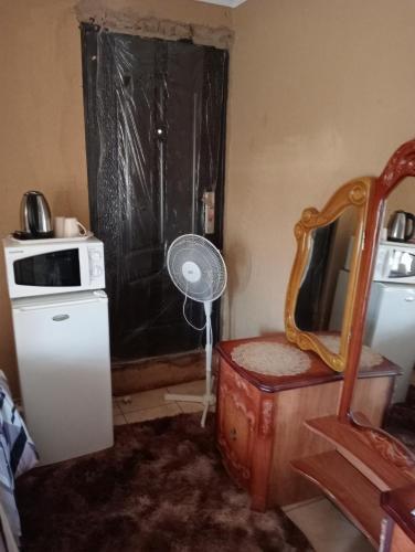 a room with a refrigerator and a window with a fan at moafrikatravellodge in Lydenburg