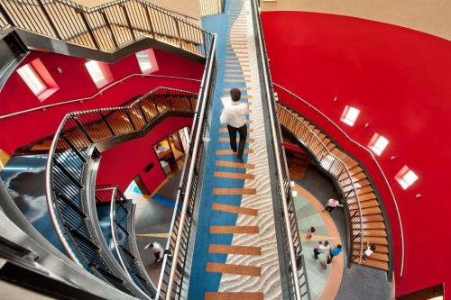a person walking down a spiral staircase in a building at Explorers Hotel Marne-la-Vallée in Magny-le-Hongre