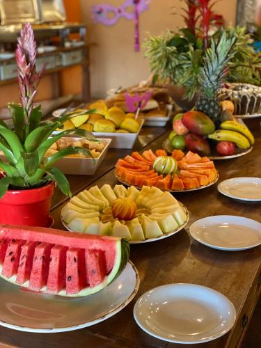 a table topped with plates of fruit and vegetables at Hotel Pousada Villa Itália Olímpia in Olímpia