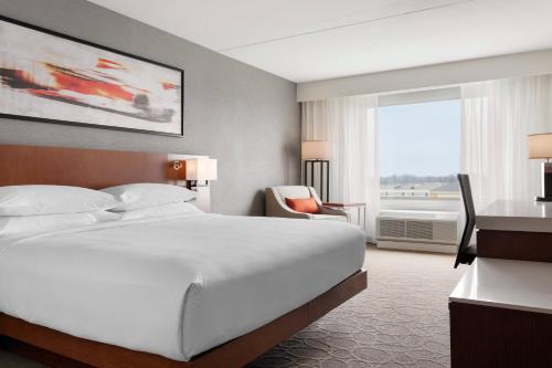 um quarto de hotel com uma grande cama branca e uma janela em Delta Hotels by Marriott - Indianapolis Airport em Indianápolis