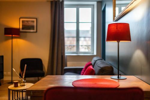 een woonkamer met een bank en een tafel met een lamp bij Escapade Place 11 - Appartement A2 Dinan centre in Dinan
