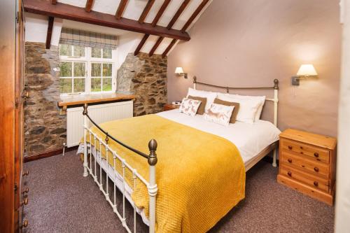 sypialnia z dużym łóżkiem i żółtym kocem w obiekcie Brynarth Country Cottages w Aberystwyth