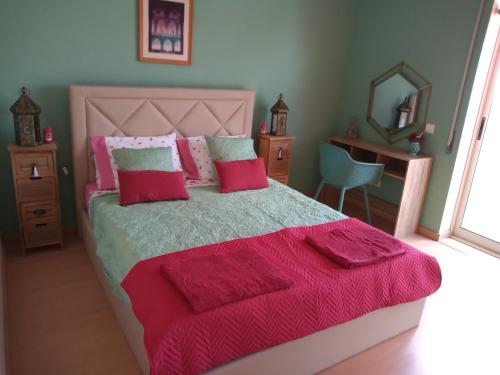 1 dormitorio con 1 cama grande con almohadas rojas y rosas en Quartos confortáveis em casa próximo ao Mosteiro en Batalha