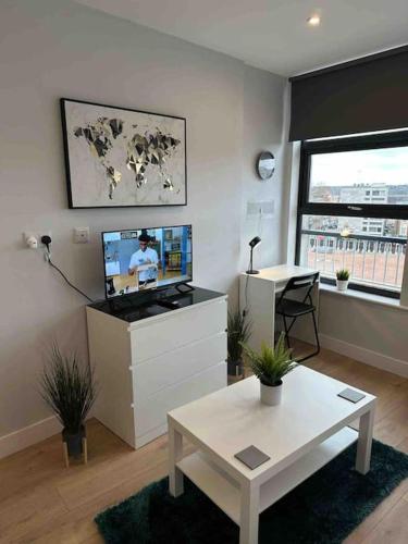 a living room with a flat screen tv and a table at King Bed Studio Apartment in Central Northampton in Northampton