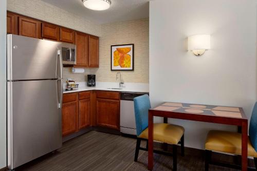 a kitchen with a refrigerator and a table with chairs at Residence Inn Saint Louis Airport / Earth City in Earth City