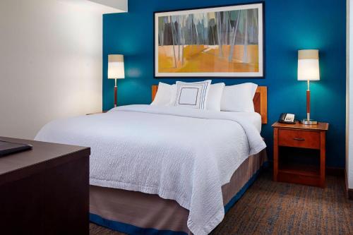 a large bed in a hotel room with blue walls at Residence Inn Saint Louis Airport / Earth City in Earth City