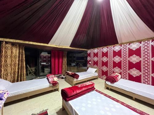 una habitación con 3 camas en una tienda de campaña en Bedouin Holidays Camp and Jeep Tours, en Wadi Rum