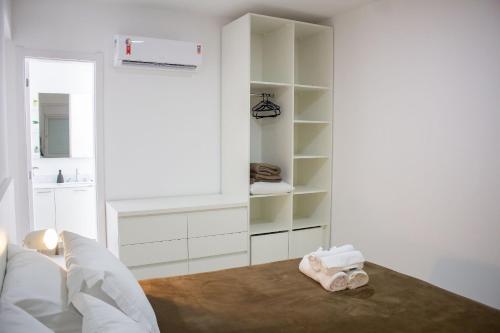 a white room with a bed and a book shelf at Atlântida Green Square - 601B in Capão da Canoa