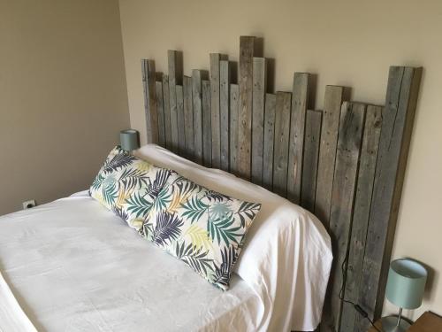 a bed with a wooden headboard in a bedroom at Cosy T2, au calme entre mer et montagnes in Saint-Pée-sur-Nivelle