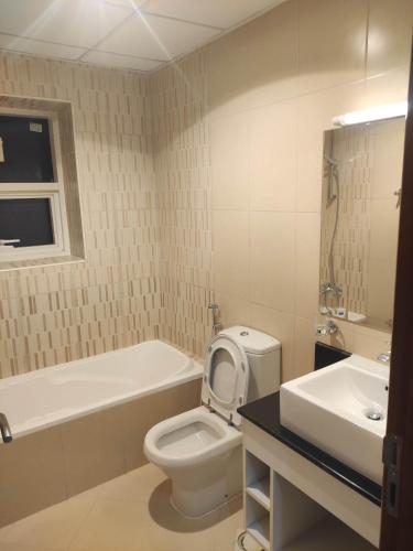 a bathroom with a toilet and a tub and a sink at Elegant Room In shared Apartment in Ajman 