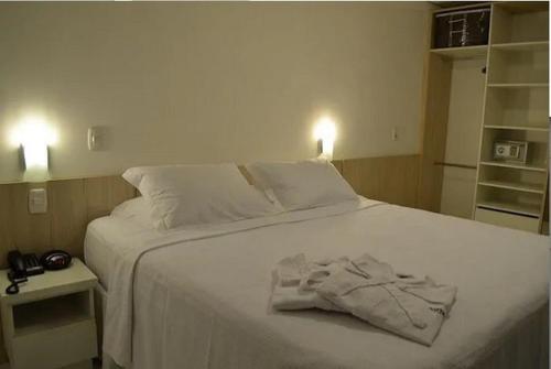 a white bed with a robe on top of it at Executive 106 Sem Garagem in Caxias do Sul