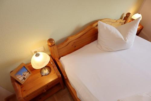 a bed with a wooden headboard and a night stand with a clock at Gasthof Rebland in Eichstetten