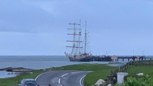a car driving down a road with a ship on the water at Loch Gorm House in Bruichladdich