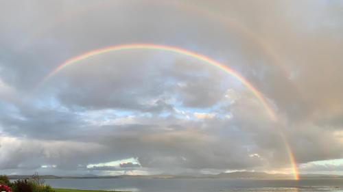 a rainbow in the sky over a body of water at Loch Gorm House in Bruichladdich