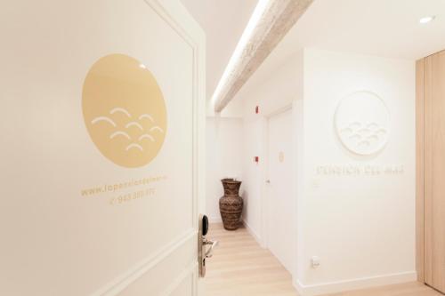 a hallway with white walls and a door with a sign on it at Pension Del Mar in San Sebastián